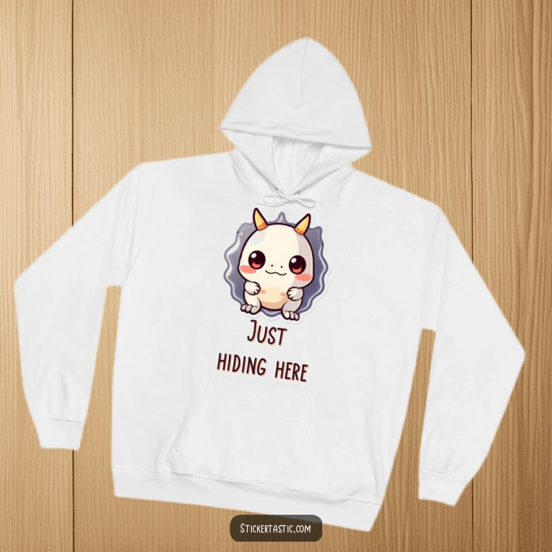 Funny monster hoodie with a charming, shy monster peeking from behind a large, reflective sticker. Embodies playful curiosity and warmth.